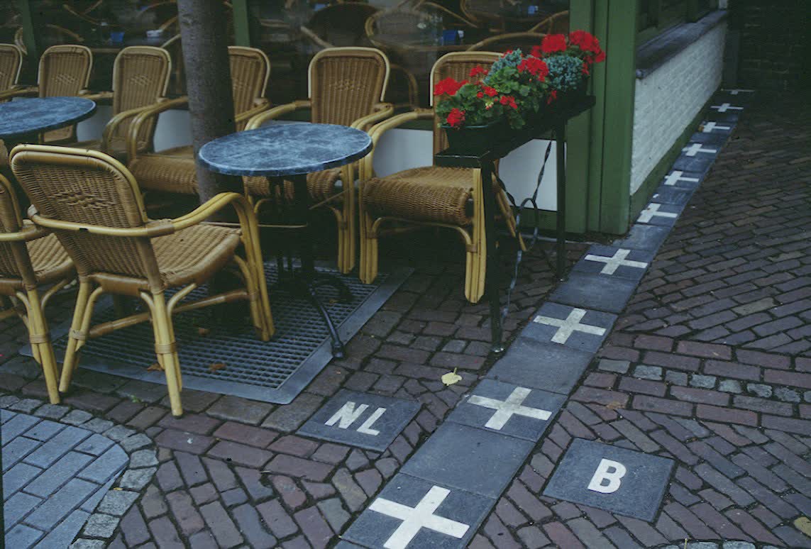 Café terrace in Baarle with the Netherlands–Belgium border marked by white crosses in the pavement between the tables