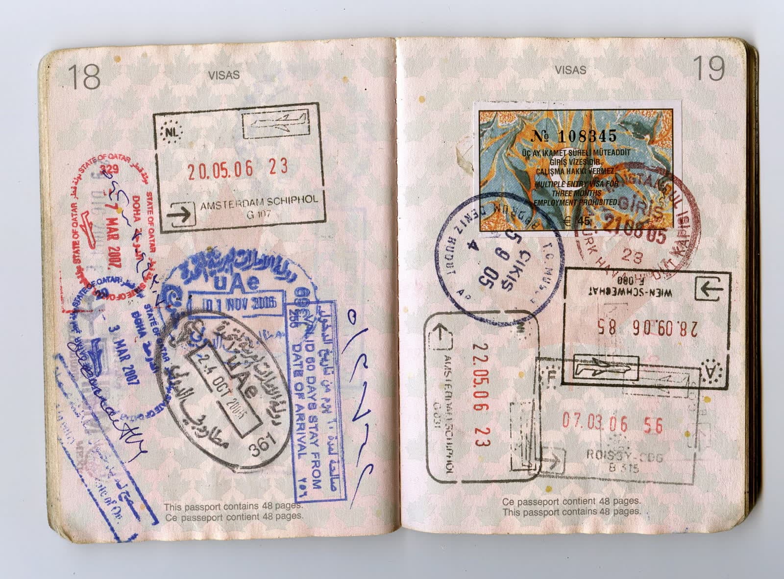 A well-travelled passport open to two pages crowded with entry and exit stamps